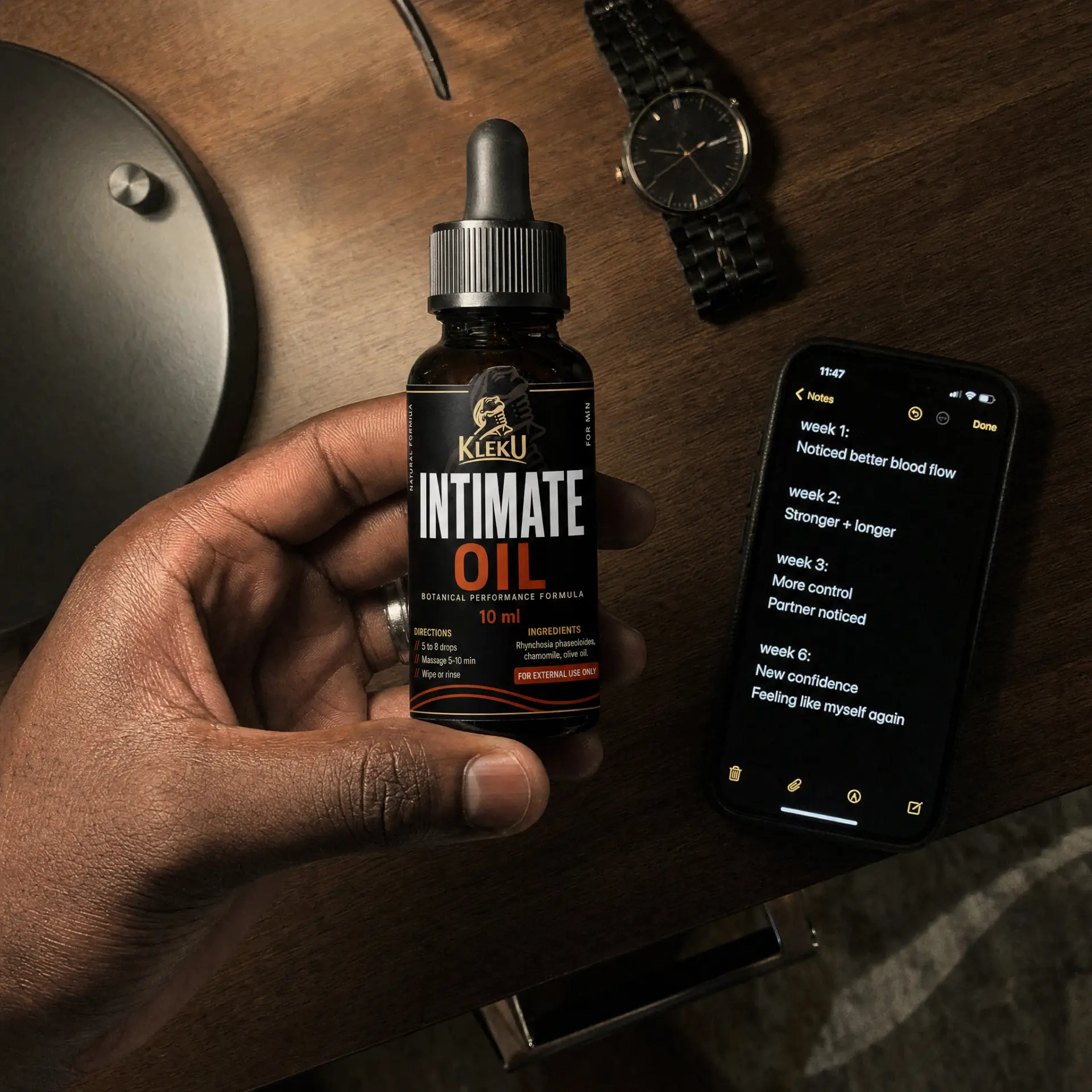 Hand holding a Kleku Intimate Oil bottle next to a phone showing weekly progress notes